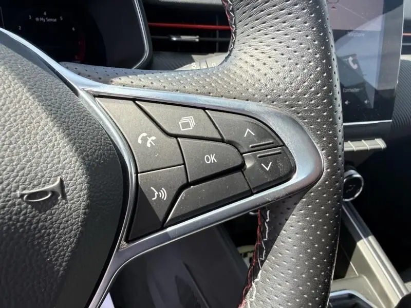 Gros plan sur les commandes au volant perforé de la Renault Clio V Rouge Flamme 2022, version RS Line essence.