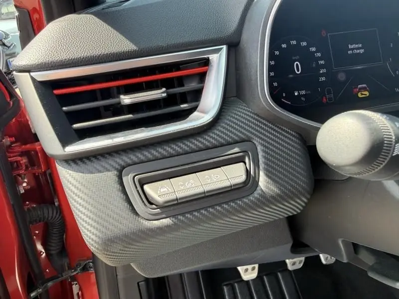 Détail intérieur côté gauche de la planche de bord de la Renault Clio V rouge flamme avec commandes d’aide à la conduite.