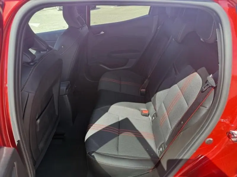 Vue intérieure arrière côté droit de la Renault Clio V rouge flamme, montrant les sièges arrière avec surpiqûres rouges.