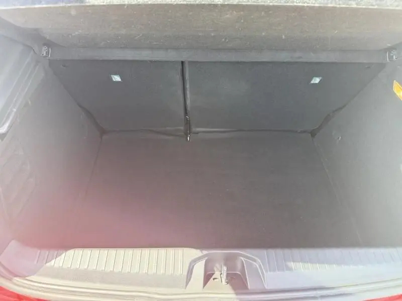 Coffre ouvert vu de dessus d'une Renault Clio V Rouge Flamme, montrant un espace de rangement vide et propre.