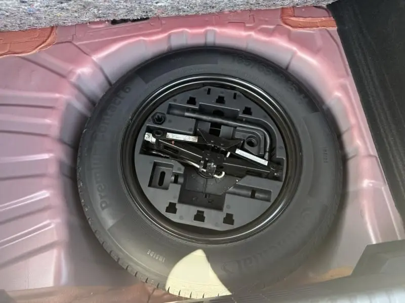 Roue de secours avec outillage intégré dans le coffre d'une Renault Clio V Rouge Flamme, vue de dessus.