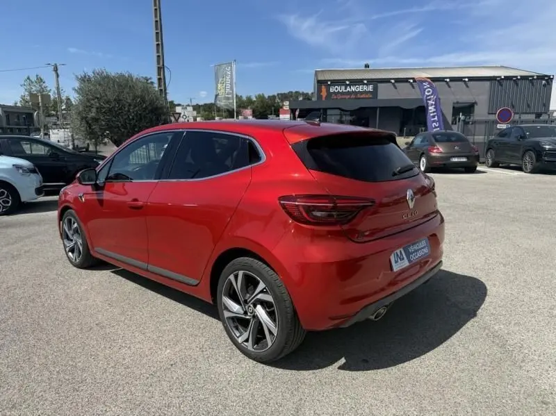 Renault Clio V Rouge Flamme vue 3/4 arrière droit, finition RS Line avec jantes alliage et vitres teintées.
