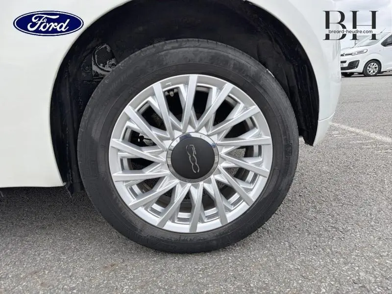 Gros plan sur la roue avant droite d'une FIAT 500 blanche Bossa Nova avec jante alu à rayons fins.