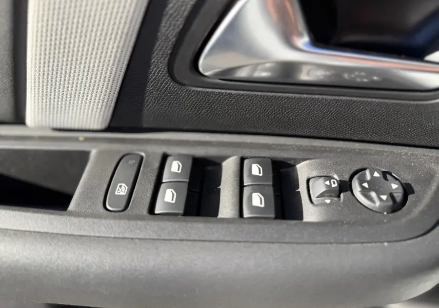 Gros plan sur les commandes de lève-vitres et rétroviseurs côté gauche d’une Citroën C4 blanche, intérieur noir.