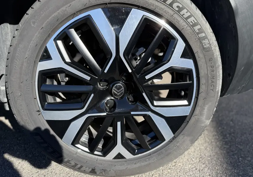 Gros plan sur la jante noire et argentée au design géométrique du Citroën C4 Hybrid 2025 en blanc Okenite.