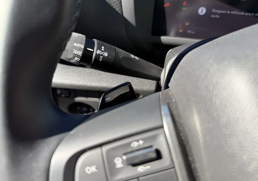 Gros plan sur le commodo d'éclairage et les commandes au volant du Citroën C4 Hybrid 145 CH, intérieur noir.