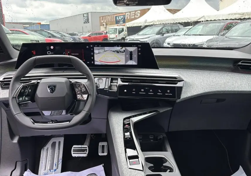 Vue intérieure du poste de conduite du Peugeot 3008 noir Perla 2026, avec volant compact et écran panoramique affichant la caméra de recul.