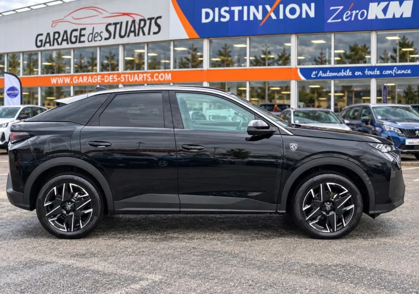 Profil droit d’un Peugeot 3008 noir perla 2026 avec jantes alliage 19’’ diamantées et vitres teintées, devant un garage.