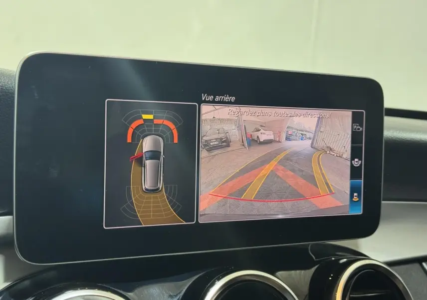 Écran central de la Mercedes Classe C Break noir 2019 montrant la caméra de recul et l'aide au stationnement active.