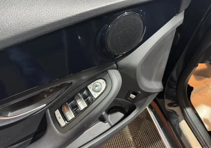 Détail de la porte côté conducteur d’un Mercedes Classe C Break noir, avec commandes des vitres et haut-parleur intégré.