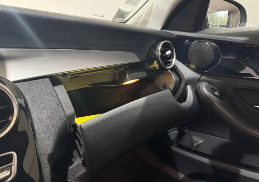Intérieur noir du Mercedes Classe C Break 2019, vue côté passager avec boîte à gants ouverte et éclairage intérieur.