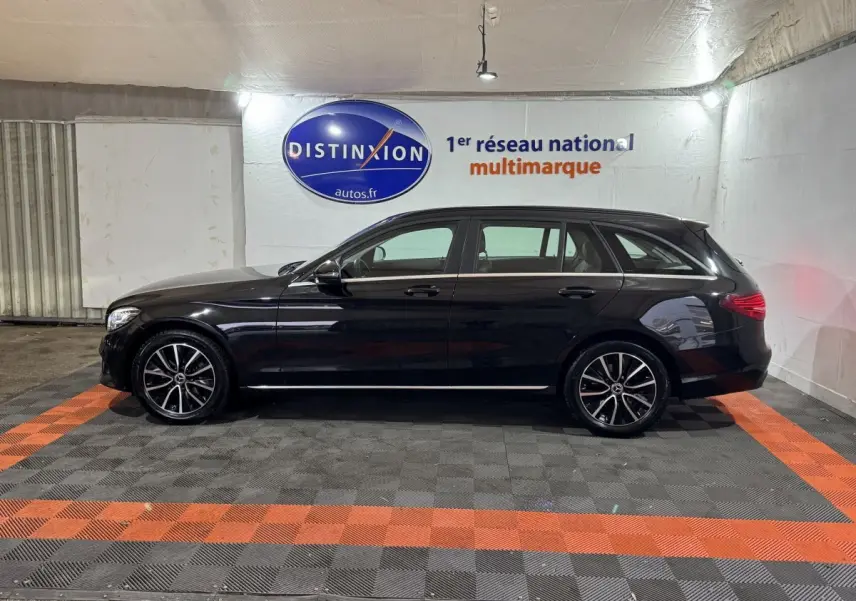 Profil côté gauche d'un break Mercedes Classe C noir 2019 avec jantes alliage et toit chromé dans un showroom.