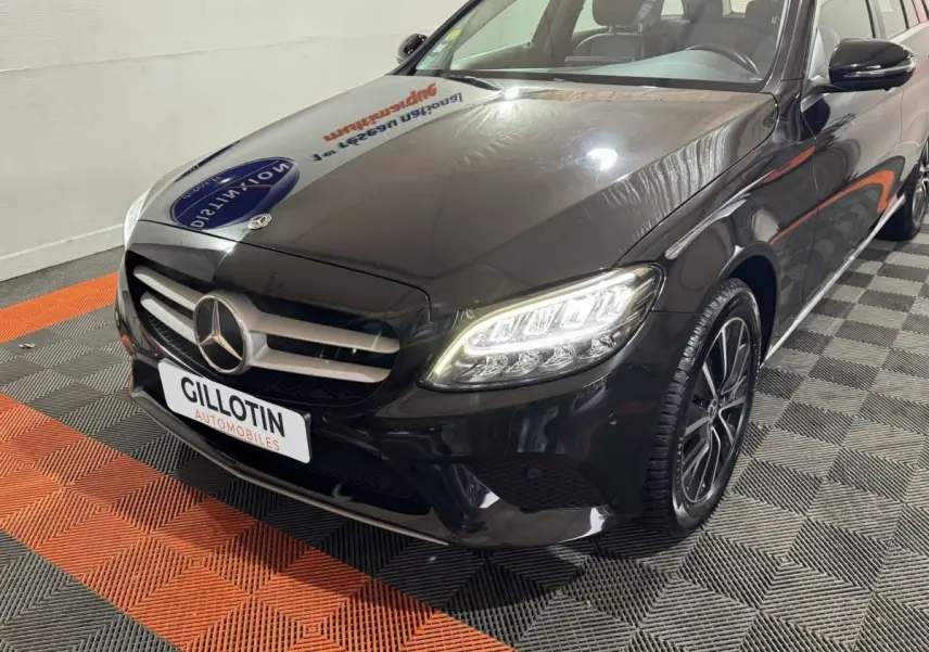Vue 3/4 avant droite d'une Mercedes Classe C Break C 200 d Business Line noire avec phares LED allumés et jantes alliage.