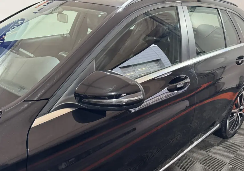 Vue rapprochée du côté gauche d'une Mercedes Classe C Break C 200 d Business Line noire, mettant en valeur la portière et le rétroviseur.