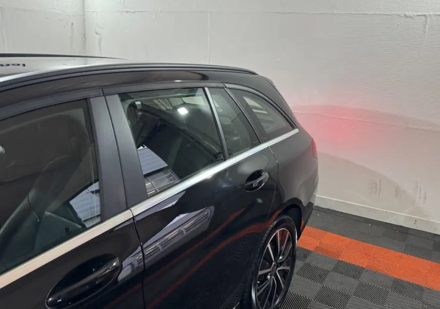 Vue latérale arrière droite d'une Mercedes Classe C Break C 200 d Business Line noire avec jantes alliage et feux arrière allumés.