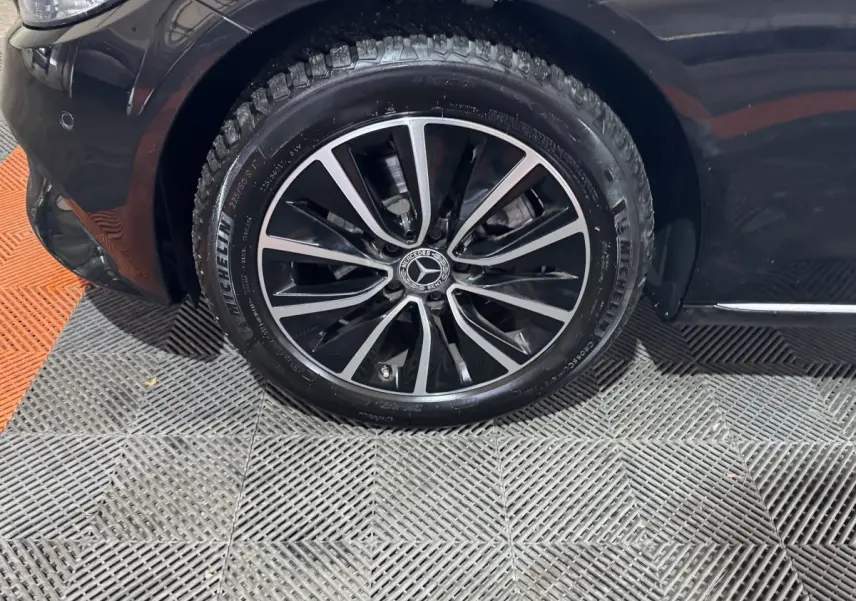 Gros plan sur la roue avant gauche noire d'une Mercedes Classe C Break C 200 d Business Line 2019 avec jante alliage bicolore.