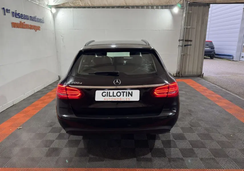 Vue arrière d'un break Mercedes Classe C 200 d noir avec feux arrière allumés dans un garage.