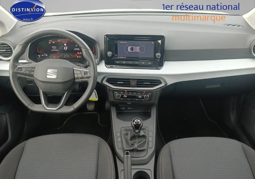 Vue intérieure frontale du poste de conduite de la SEAT Ibiza 2025 avec volant cuir, tableau de bord digital et levier de vitesse manuel.