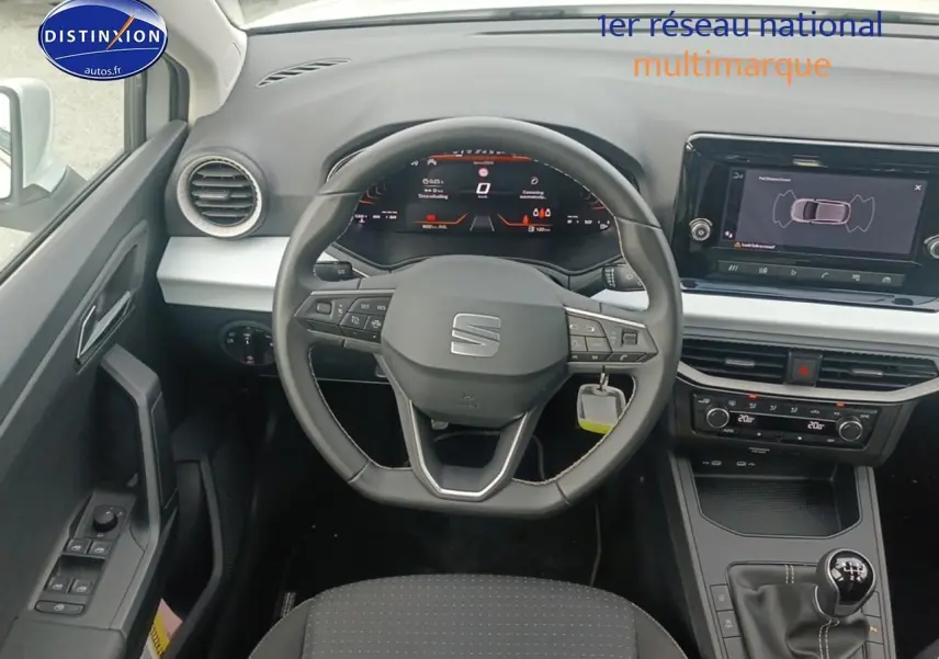 Vue intérieure centrée sur le volant cuir méplat et tableau de bord numérique de la SEAT Ibiza blanche Nevada 2025.