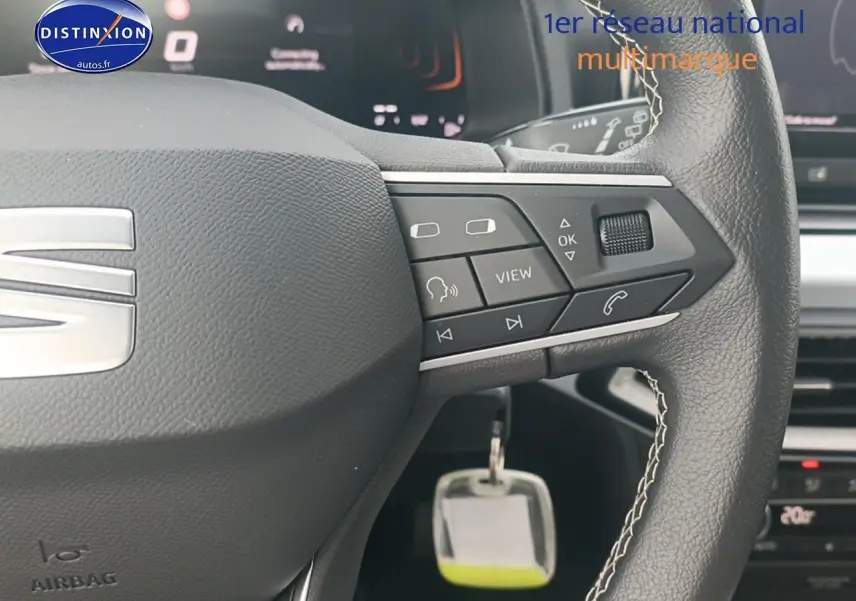 Gros plan sur le volant cuir noir multifonction de la SEAT Ibiza 2025 avec commandes intégrées et logo argenté.