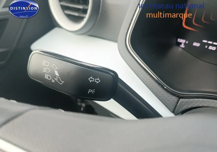 Gros plan sur la manette de clignotant à gauche du volant dans l’habitacle blanc et noir d’une SEAT Ibiza 2025.