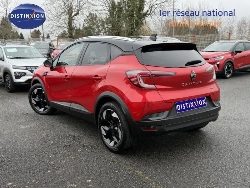 Vue 3/4 arrière droite d'un Renault Captur 2025 rouge flamme avec toit noir et jantes noires brillantes.