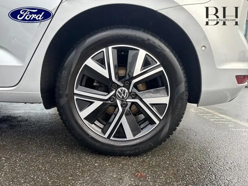 Gros plan sur la roue avant droite d’un Volkswagen Touran argent métallisé avec jante alliage bicolore et logo VW central.