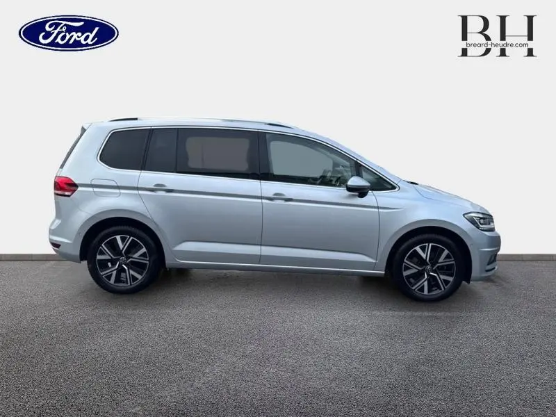 Profil droit d'un Volkswagen Touran 1.5 TSI EVO 2021 en Reflet d'Argent Métallisée avec jantes alliage et vitres teintées.