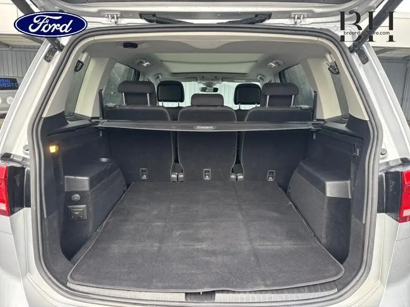 Coffre ouvert d'un Volkswagen Touran 1.5 TSI argent métallisé, vue arrière montrant les sièges rang 2 et 3.