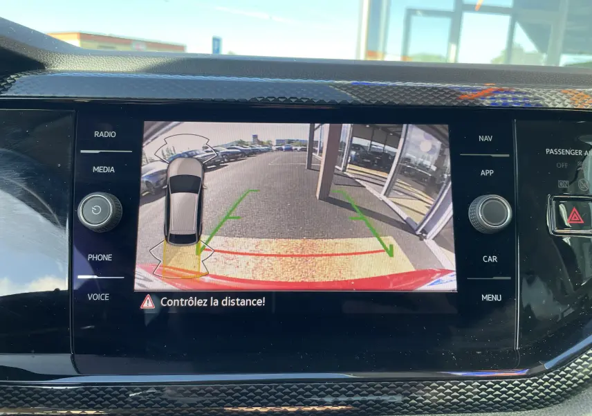 Affichage de la caméra de recul du Volkswagen Taigo rouge roi, vue arrière avec repères de distance et alerte de proximité.