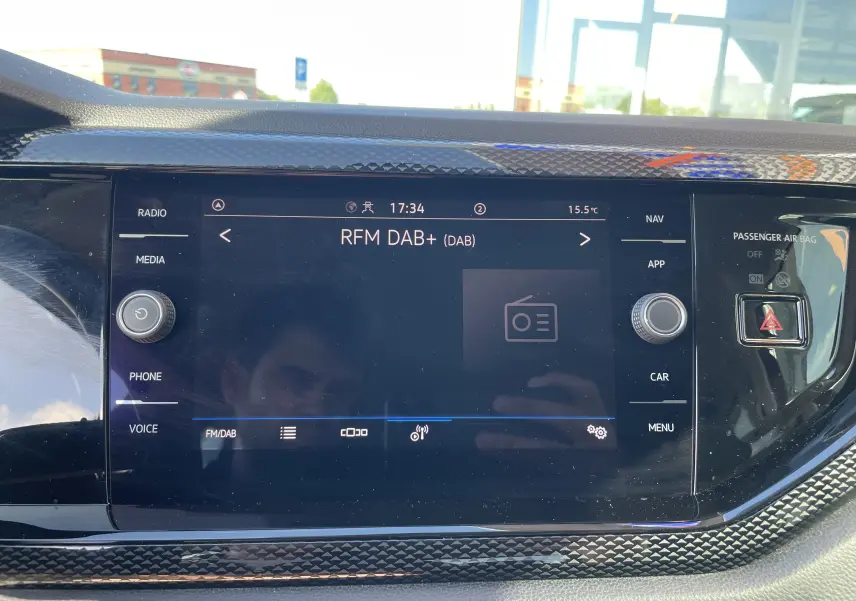 Tableau de bord du Volkswagen Taigo 2024 avec écran tactile central allumé, entouré d’un cadre noir texturé.