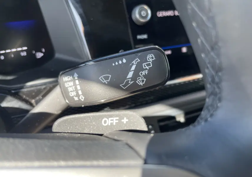 Gros plan sur la commande d’essuie-glace à gauche du volant dans l’habitacle du Volkswagen Taigo rouge Roi 2024.