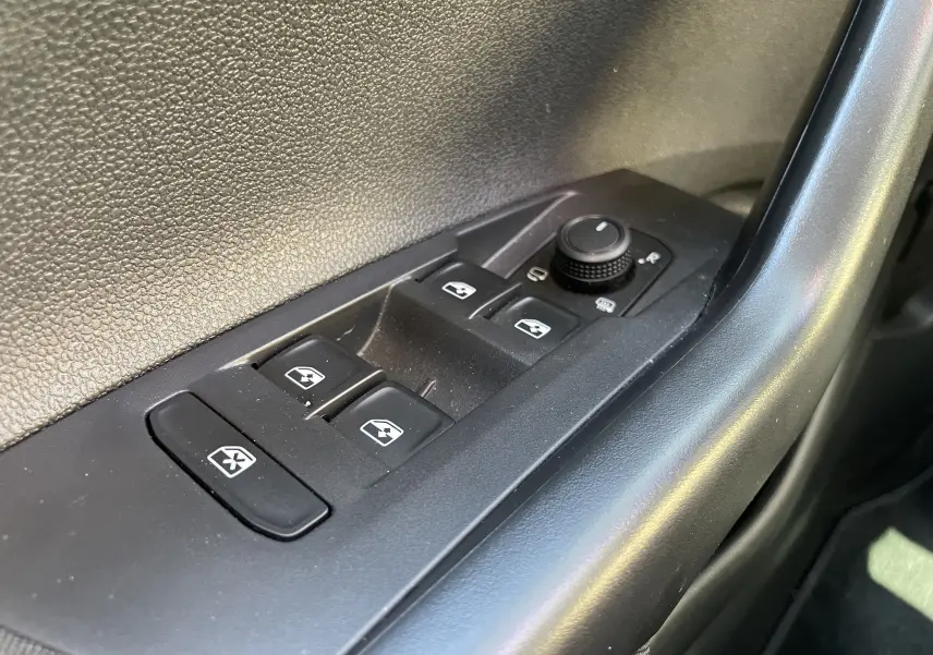 Gros plan sur les commandes des vitres électriques et rétroviseurs sur la porte côté conducteur d'un Volkswagen Taigo 2024.