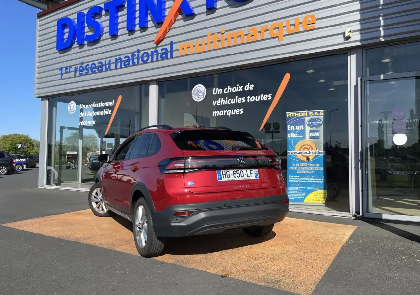 Volkswagen Taigo rouge Roi vue 3/4 arrière droit, stationné devant un showroom Distinxion.