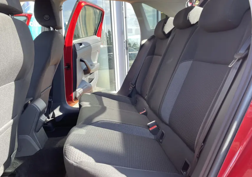 Vue intérieure côté droit des sièges arrière en tissu gris noir du Volkswagen Taigo rouge Roi avec porte arrière ouverte.
