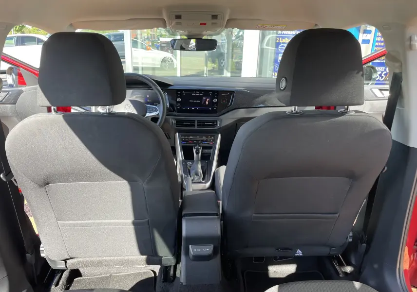 Vue intérieure arrière du Volkswagen Taigo rouge Roi 2024, montrant les sièges avant noirs et le tableau de bord moderne.