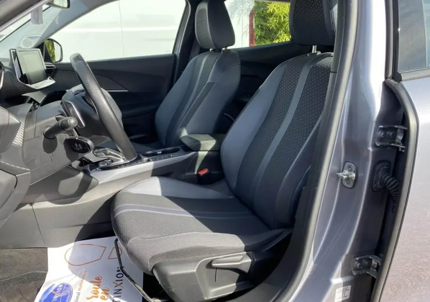 Vue intérieure côté conducteur de la Peugeot 2008 gris clair, montrant les sièges avant et la console centrale avec boîte auto.
