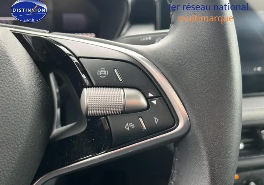 Gros plan sur les commandes multifonctions en métal et plastique noir du volant cuir d'une Skoda Fabia blanche 2025.