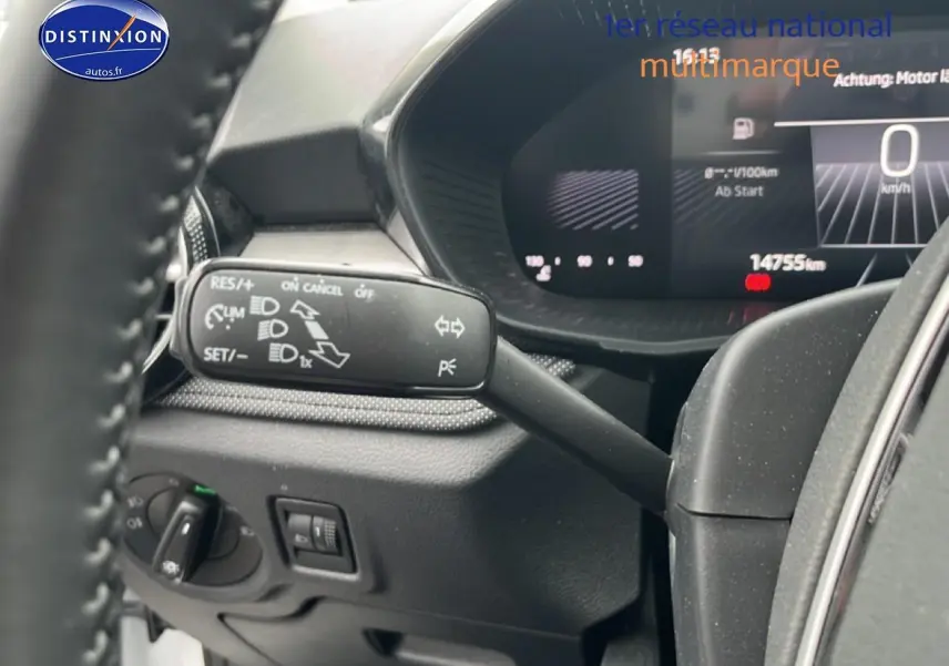 Détail du commodo de clignotant et tableau de bord numérique d'une Skoda Fabia blanche, vue intérieure côté conducteur.
