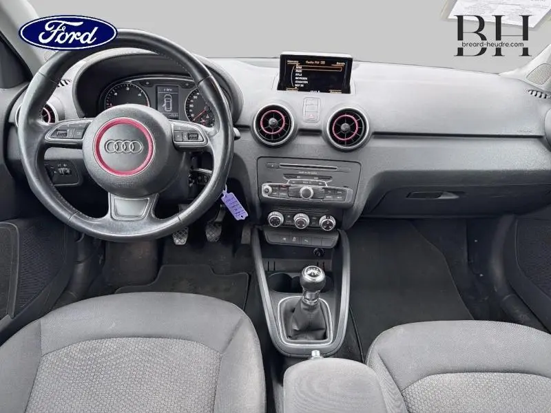 Intérieur avant d’Audi A1 Sportback noir, vue centrée sur tableau de bord, volant cuir multifonction et boîte manuelle.