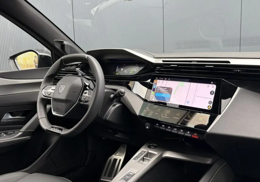 Vue intérieure côté conducteur du Peugeot 308 SW gris, avec volant compact GT et écran tactile central lumineux.