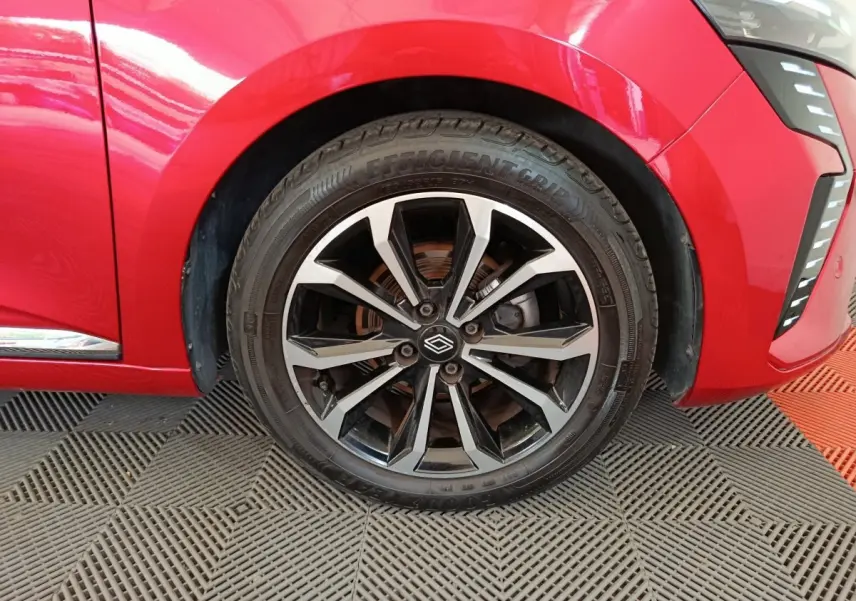Gros plan sur la roue avant droite d'une Renault Clio Techno TCe 90 rouge 2024 avec jante alliage noire et argent.