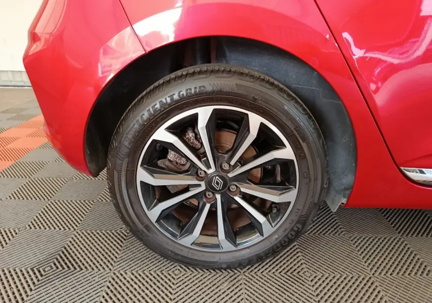 Gros plan sur la roue arrière droite d’une Renault Clio rouge 2024 avec jante alliage bicolore et logo Renault central.