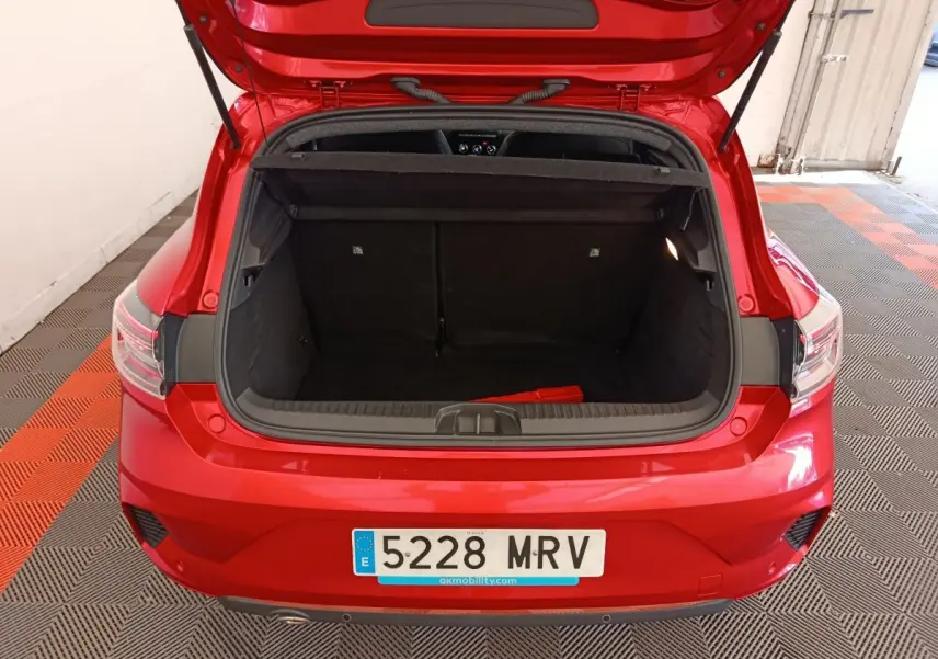 Vue arrière ouverte du coffre d'une Renault Clio Techno TCe 90 rouge 2024, montrant l'espace de chargement vide.