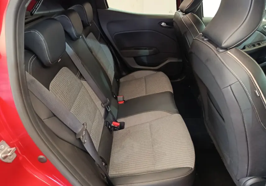 Vue intérieure côté arrière gauche de la Renault Clio rouge 2024, mettant en valeur la banquette arrière bicolore tissu et cuir.