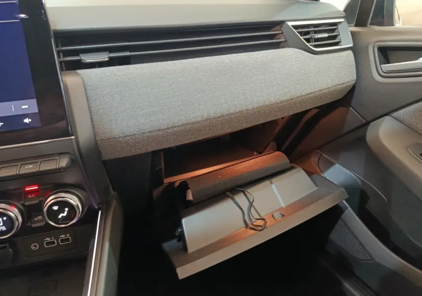 Intérieur de la Renault Clio Techno TCe 90 2024, vue côté passager avec boîte à gants ouverte et tableau de bord gris.