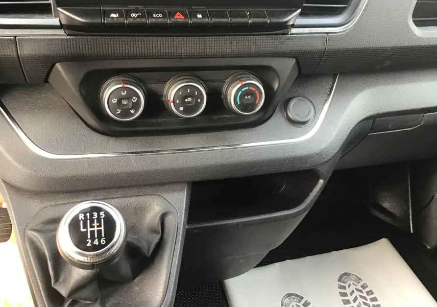 Gros plan sur la console centrale du Renault Trafic blanc 2022, montrant la boîte manuelle et les commandes de climatisation.