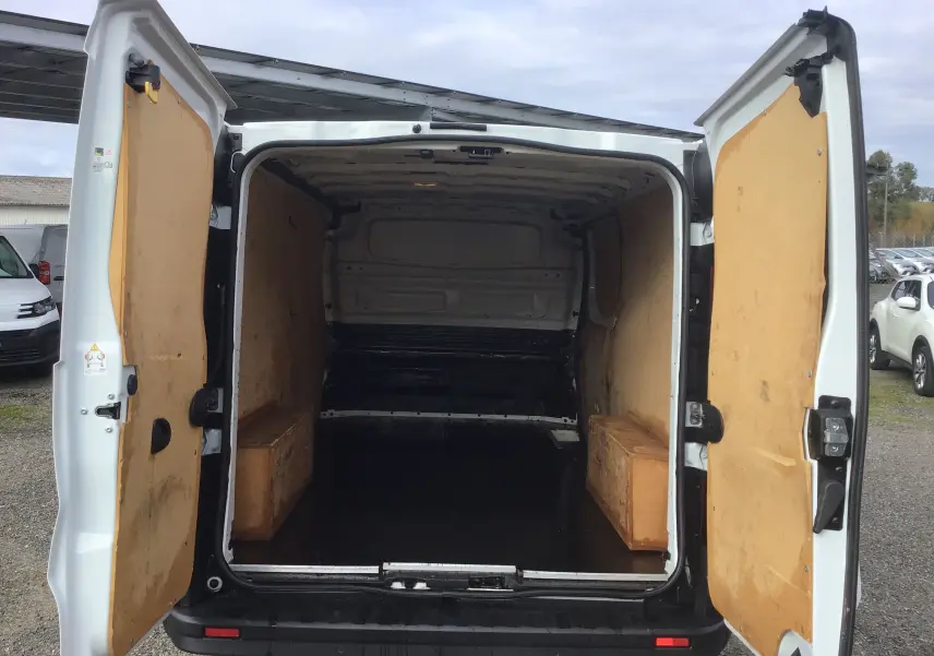 Vue arrière ouverte du Renault Trafic Fourgon blanc, montrant l'espace de chargement avec parois en bois.