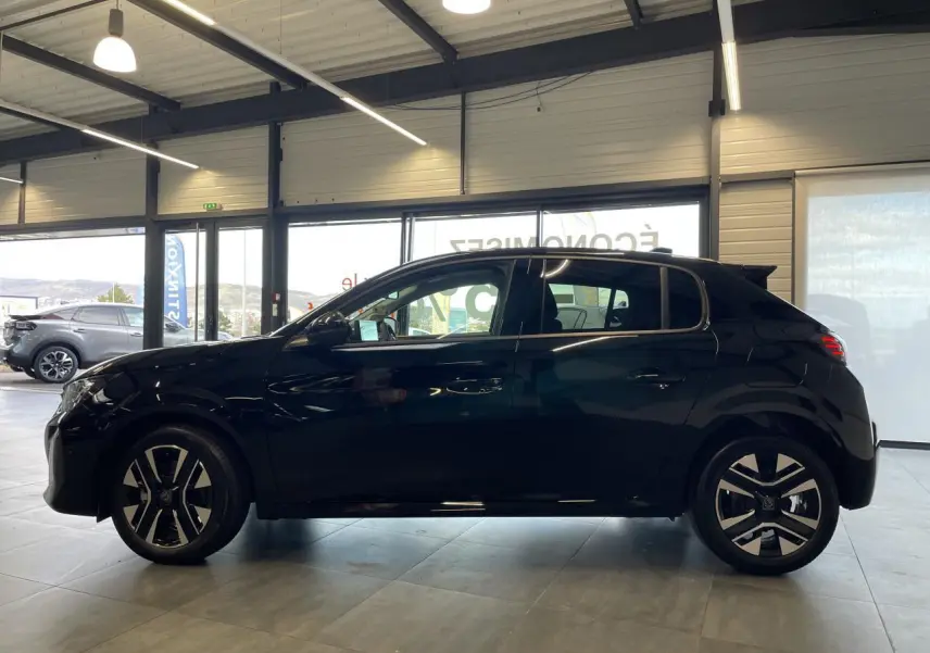 Profil latéral droit d'une Peugeot 208 noire métallisée 2025 en showroom avec jantes alliage bi-ton et feux arrière à LED.
