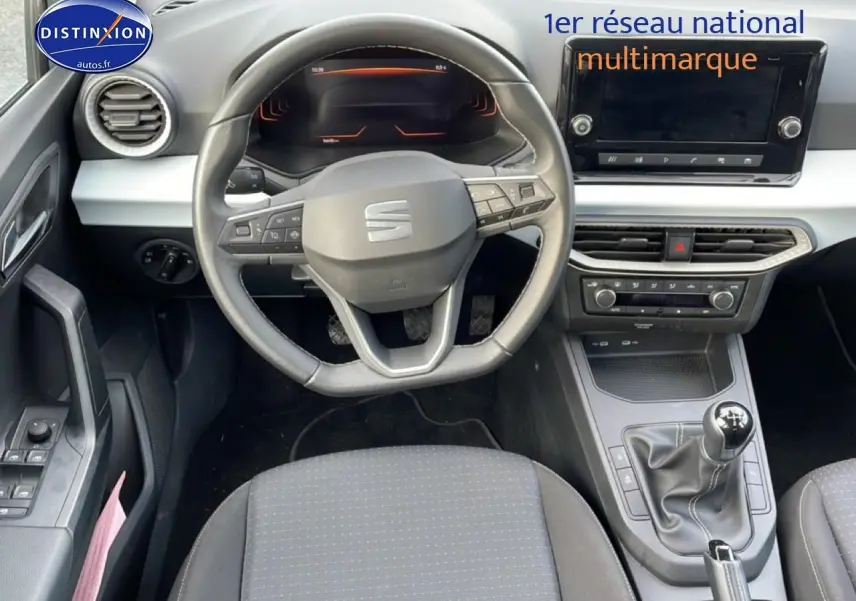 Vue intérieure frontale du poste de conduite de la SEAT Ibiza blanc Nevada 2025 avec volant sport et boîte manuelle.